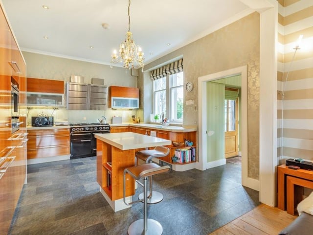 Kitchen with range of wall and base units including a central island with breakfast bar, and modern integrated appliances.