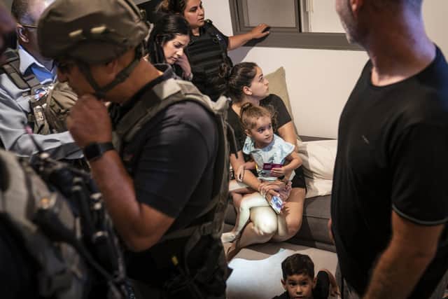 A family huddles in their home with bomb technicians and police as sirens warn of an incoming attack on Thursday in Ashkelon, southern Israel. Their home had just received a direct hit from a missile that failed to explode (Picture: John Minchillo/AP)