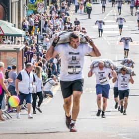 Competitors take part in the Scottish Coal Carrying Championships through the streets of Kelty in Fife.  Picture date: Saturday August 28, 2021. PA Photo. The annual event is one of only two Coal Races in the world and the men's race requires participants to carry a 50-kilo bag of coal and the women's race requires a 25-kilo bag of coal to be carried over 1000 metres through the village. Photo credit should read: Jane Barlow/PA Wire 
