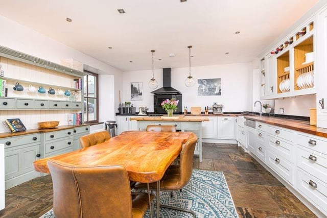 The open plan kitchen/dining area is a substantial space, fitted with wall and base units and solid wood counters, as well as a hood and induction hob and cooker, an integrated dish washer and boiling water tap.