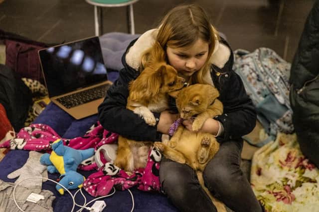 A girl sits with her dog and cat in the Dorohozhychi subway station which has has been turned into a bomb shelter in Kyiv, Ukraine.