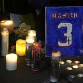 A painting that shows the number of Buffalo Bills' Damar Hamlin is illuminated by candles during a prayer vigil outside University of Cincinnati Medical Center, Tuesday, Jan. 3, 2023, in Cincinnati.