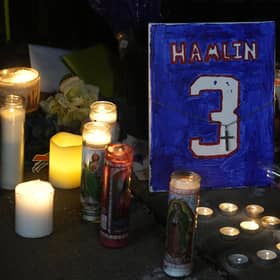 A painting that shows the number of Buffalo Bills' Damar Hamlin is illuminated by candles during a prayer vigil outside University of Cincinnati Medical Center, Tuesday, Jan. 3, 2023, in Cincinnati.