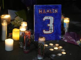 A painting that shows the number of Buffalo Bills' Damar Hamlin is illuminated by candles during a prayer vigil outside University of Cincinnati Medical Center, Tuesday, Jan. 3, 2023, in Cincinnati.