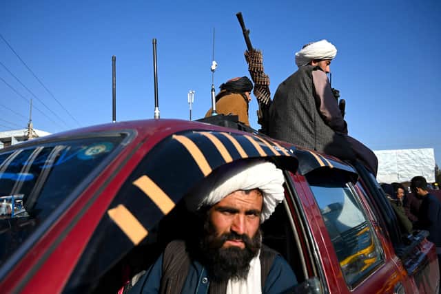 Taliban fighters sit on a vehicle along a road in the Herat.