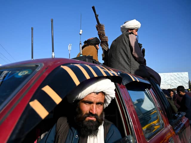 Taliban fighters sit on a vehicle along a road in the Herat.