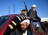 Taliban fighters sit on a vehicle along a road in the Herat.
