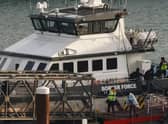 Migrants picked up at sea while attempting to cross the English Channel are escorted off from a UK Border Force boat upon arrival at the Marina in Dover, southeast England, last year.