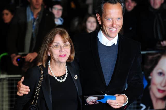 (FILE PHOTO) Actor Richard E Grant has paid tribute to his wife of 35 years Joan Washington in a heartfelt message on social media after she reportedly died last night. British actor Richard E Grant (R) poses with his wife Joan Washington (L) on the blue carpet as she arrives to attend the European premiere of the film "The Iron Lady" at BFI Southbank in London on January 4, 2012. The biopic set in the present day is a story of ambition; power won and power lost; and also love, with flashes of memory whisking the viewer off to a time when Margaret Thatcher, played by Meryl Streep, was the Western world's first female leader and possibly Britain's most divisive prime minister. AFP PHOTO / LEON NEAL (Photo credit should read LEON NEAL/AFP via Getty Images)