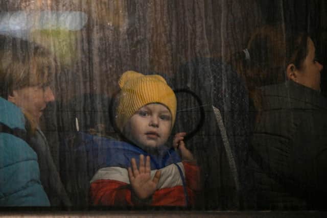 A child greets from the window of a bus after crossing the Ukrainian border with Poland at the Medyka border crossing