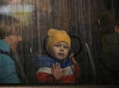 A child greets from the window of a bus after crossing the Ukrainian border with Poland at the Medyka border crossing