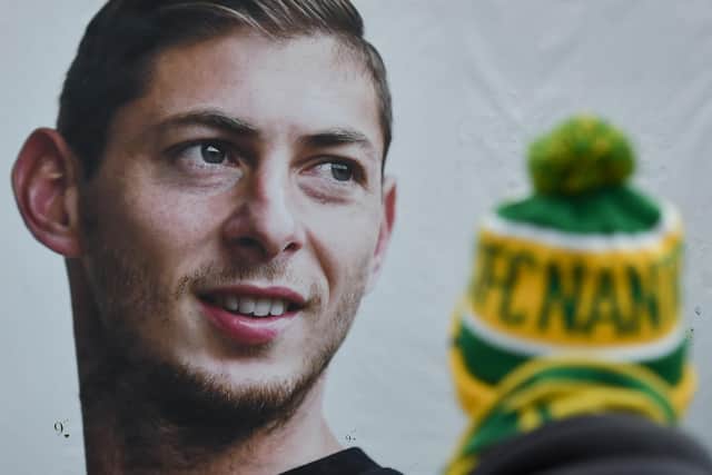 A person stands in front of a portrait of Nantes' Argentinian forward Emilianio Sala, who died last year in a plane crash (Photo by SEBASTIEN SALOM-GOMIS/AFP via Getty Images)