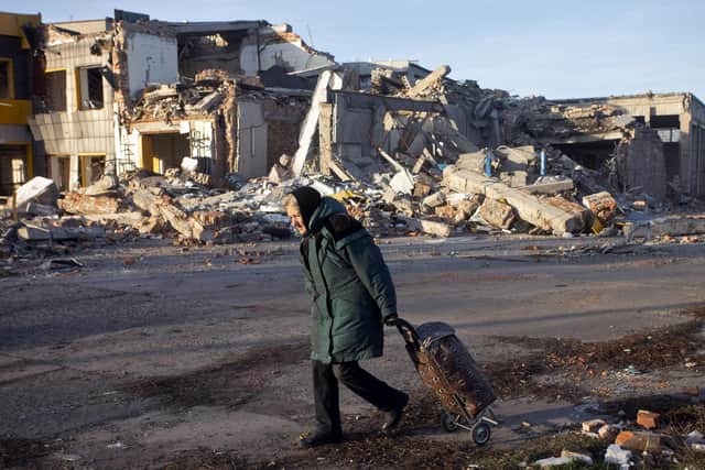 An elderly woman pulls a trolley bag past a the ruins of a building in Bakhmut, one of ten Ukrainian cities destroyed by Russian forces, in December (Picture: Yevhen Titov/AFP via Getty Images)