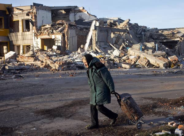 An elderly woman pulls a trolley bag past a the ruins of a building in Bakhmut, one of ten Ukrainian cities destroyed by Russian forces, in December (Picture: Yevhen Titov/AFP via Getty Images)