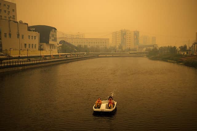 A couple rides a pedal boat as smoke from nearby forest fires hangs over the city of Yakutsk in Siberia (Picture: Dimitar Dilkoff/AFP via Getty Images)