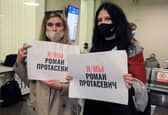 Women with posters reading 'I am/we are Roman Protasevich' in the arrival area as passengers disembark from the Ryanair passenger plane from Athens that was intercepted and diverted to Minsk on the same day by Belarus authorities on 23 May (Photo: PETRAS MALUKAS/AFP via Getty Images)