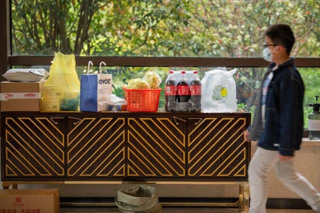 A resident walks in front of the food and daily necessities which be bartered by neighbours at an apartment lobby in a compound during lockdown in Pudong district in Shanghai.
