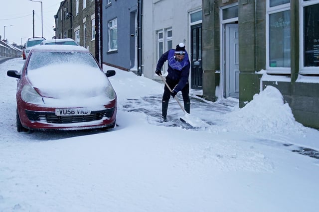 A man clears snow from the road in Tow Law, Co Durham, after heavy overnight snow fall.