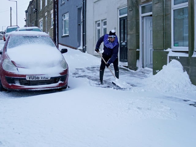A man clears snow from the road in Tow Law, Co Durham, after heavy overnight snow fall.