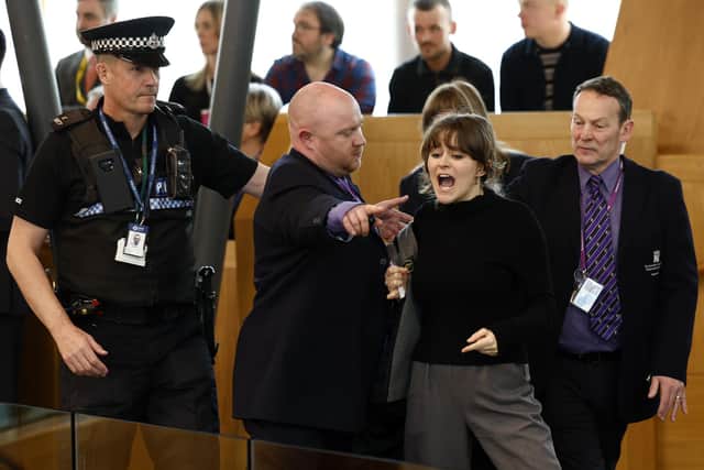 Police and security staff escort a protester from the public gallery during First Minister's Questions at Scottish Parliament (Picture: Jeff J Mitchell/Getty Images)