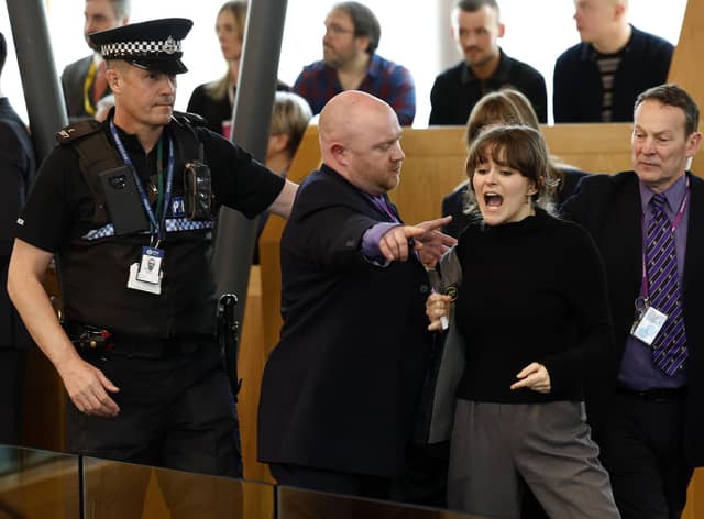 Police and security staff escort a protester from the public gallery during First Minister's Questions at Scottish Parliament (Picture: Jeff J Mitchell/Getty Images)