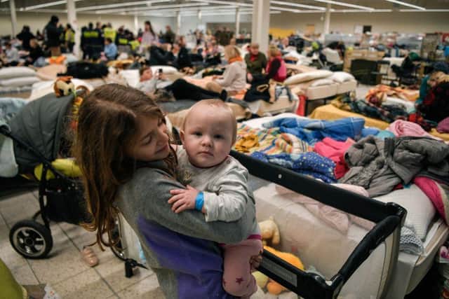 A girl plays with a an infant in a temporary shelter hosting Ukrainian refugees located in a former shopping centre near the Polish city of Przemysl.