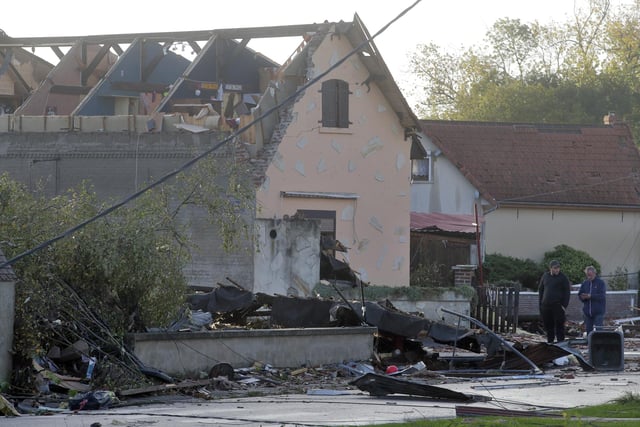 People stand next to a house whose roof was destroyed by a tornado, in Bihucourt, northern France. Tornado-like storms that tore through northern France sheared off part of a church roof, felled trees and power lines and left scores of people without a safe place to live, authorities said Monday. (AP Photo/Michel Spingler)