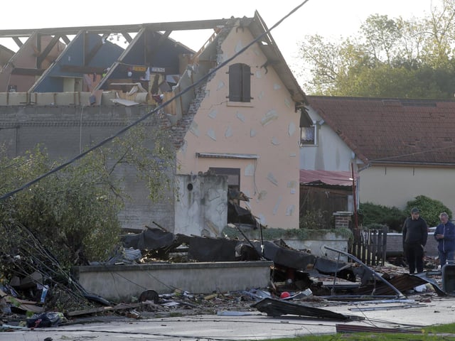 People stand next to a house whose roof was destroyed by a tornado, in Bihucourt, northern France. Tornado-like storms that tore through northern France sheared off part of a church roof, felled trees and power lines and left scores of people without a safe place to live, authorities said Monday. (AP Photo/Michel Spingler)