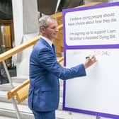 Liam McArthur signs a pledge card in support of his Assisted Dying Bill, at the Scottish Parliament