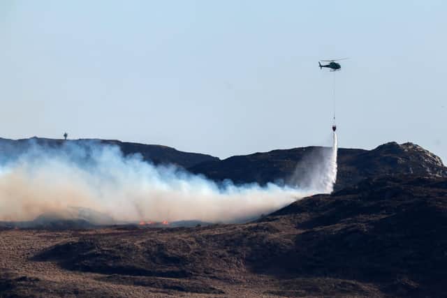 A helicopter douses a wild fire with water on the Isle of Bute on April 10 in Colintraive, Scotland. (Photo by Jeff J Mitchell/Getty Images)