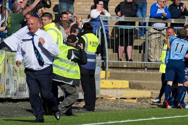 The Forfar players mob Gavin Swankie (4th from right) after his late winner in extra time as manager Dick Campbell celebrates on the touchline back in 2013.