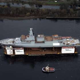 HMS Glasgow, the first of the new Type 26 frigates, sailing on a submergible barge being towed down the Clyde on her way to Geln Mallan on Loch Long. Picture: John Devlin.