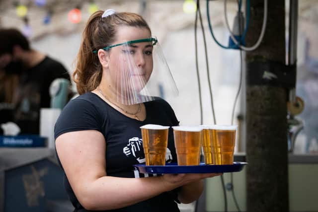 A member of staff serves drinks in the beer garden at the Bier Halle in Glasgow during the lockdown easing last summer.
