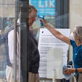 A retail worker  takes the temperature of a customer entering the Apple Store on Princes Street in Edinburgh on June 29, 2020