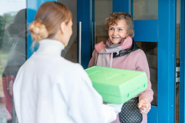 A hot meal is delivered to the door of a senior citizen Picture posed by models and from Adobe