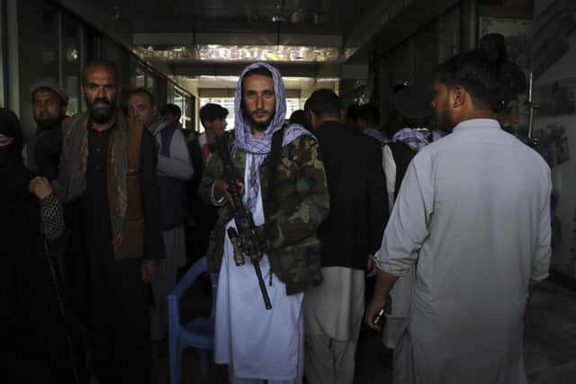 Taliban fighters stand guard by a black market currency exchange at Sarai Shahzada market in Kabul, Afghanistan, Saturday, Sept. 4, 2021. (AP Photo/Wali Sabawoon)