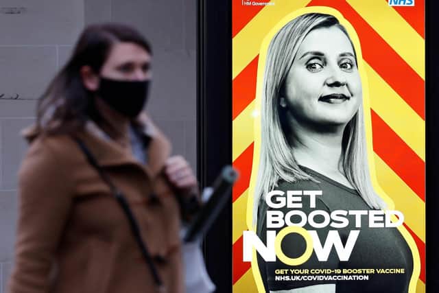 A pedestrian walks past an electronic billboard promoting Britain's NHS Covid-19 vaccine booster programme, in central London. Picture: Tolga Akmen/AFP via Getty Images