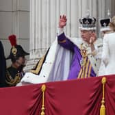 The Prince of Wales looks on as King Charles III, wearing the Imperial State Crown, and Queen Camilla, wearing a modified version of Queen Mary's Crown, wave on the balcony of Buckingham Palace, London, following the coronation.