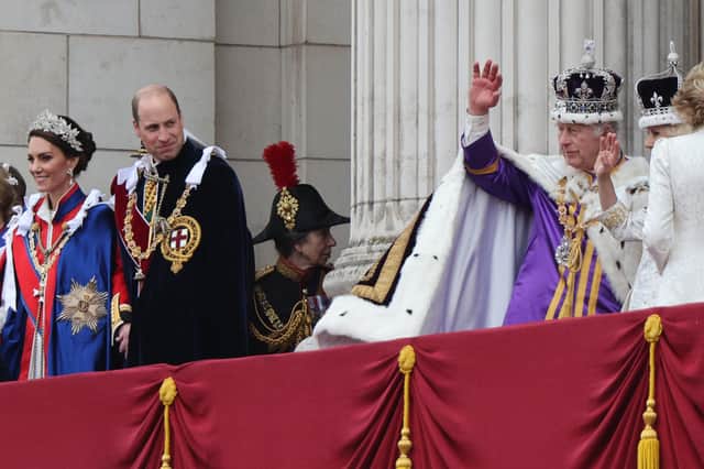 The Prince of Wales looks on as King Charles III, wearing the Imperial State Crown, and Queen Camilla, wearing a modified version of Queen Mary's Crown, wave on the balcony of Buckingham Palace, London, following the coronation.