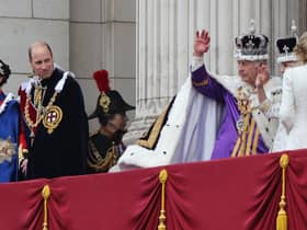 The Prince of Wales looks on as King Charles III, wearing the Imperial State Crown, and Queen Camilla, wearing a modified version of Queen Mary's Crown, wave on the balcony of Buckingham Palace, London, following the coronation.
