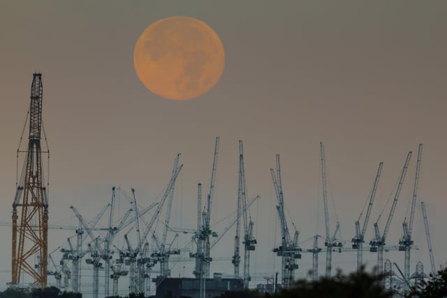 Hunter's Moon setting behind the Hinkley Point C Nuclear Power Station Construction Site on the edge of Bridgwater Bay, Somerset.