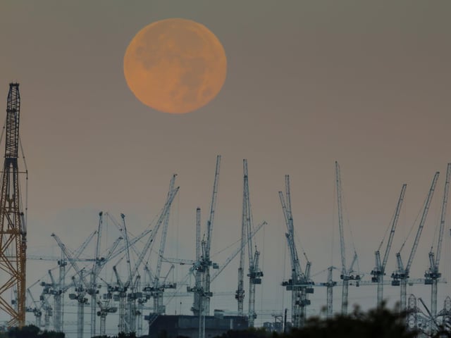 Hunter's Moon setting behind the Hinkley Point C Nuclear Power Station Construction Site on the edge of Bridgwater Bay, Somerset.