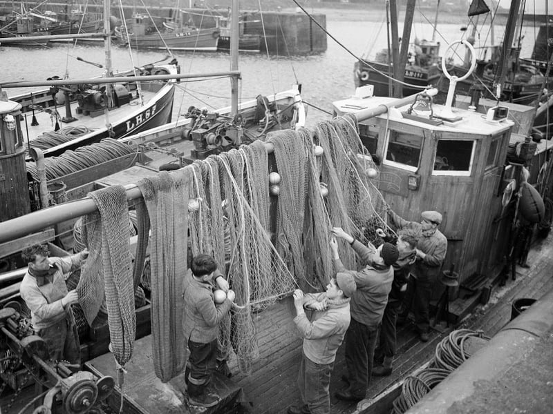 Fishermen home for New Year tidy up their nets and prepare to leave their boats at Port Seton Harbour, 1960s