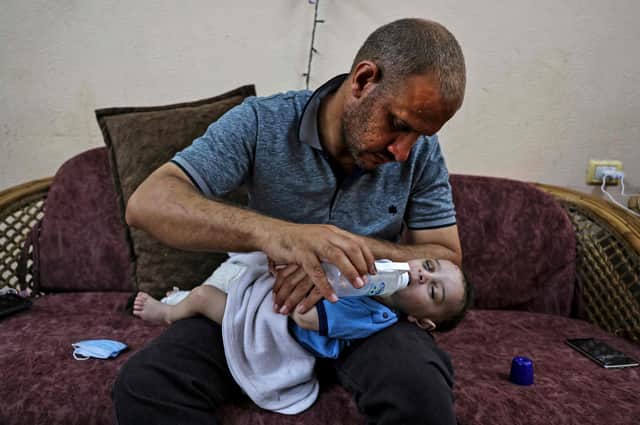 Mohammad al-Hadidi feeds his son Omar, who was pulled alive from the rubble of a building destroyed by an Israeli airstrike on the Shati refugee camp. All his other children, Suhayb, 13, Yahya, 11, Abderrahman, eight, and Osama, six, and their mother Maha Abu Hattab, 36, were killed, (Picture: Mahmud Hams/AFP via Getty Images)
