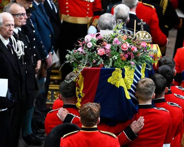 The coffin of Queen Elizabeth II with the Imperial State Crown resting on top is carried by the Bearer Party into Westminster Abbey during the State Funeral of Queen Elizabeth II.