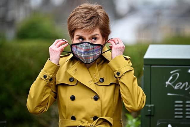 First Minister and leader of the SNP Nicola Sturgeon puts on a mask following a visit to Burnside chemist during campaigning in Rutherglen. Picture: Jeff J Mitchell/Getty Images