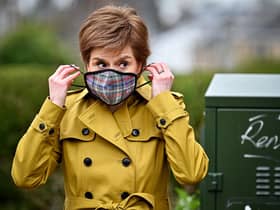 First Minister and leader of the SNP Nicola Sturgeon puts on a mask following a visit to Burnside chemist during campaigning in Rutherglen. Picture: Jeff J Mitchell/Getty Images