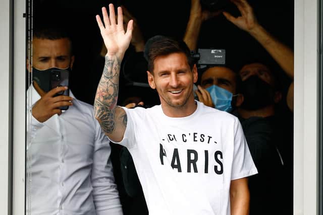 TOPSHOT - Argentinian football player Lionel Messi waves to supporters from a window after he landed at Le Bourget airport, north of Paris.
