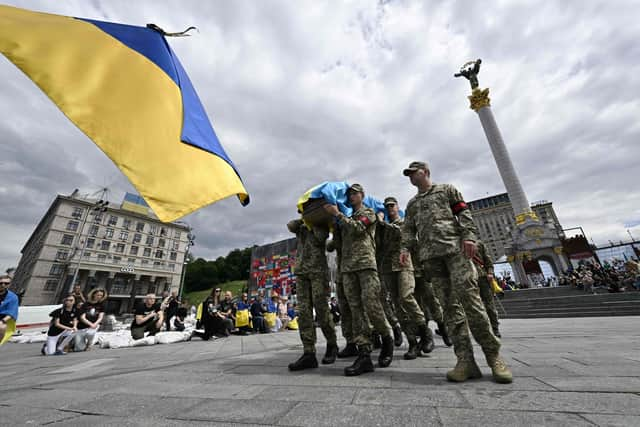 People kneel as Ukrainian soldiers carry the coffin during the farewell ceremony for Ukrainian serviceman Roman Ratushny in Kyiv. Picture: Genya Savilov/AFP via Getty Images