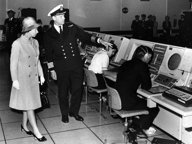 Captain S.A. Stuart, Director of the Maritime Tactical School escorts Queen Elizabeth and explains 'war games' during her visit to the Monitor room at HMS Dryad on the 20th July 1973. Picture: The News 7964-16